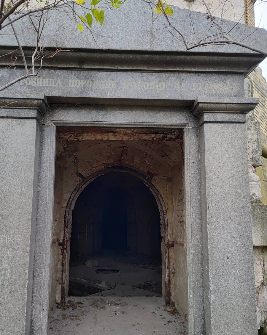 L’entrée en granit du tombeau : un linteau portant une inscription cyrillique, et au-delà un passage voûté sombre.